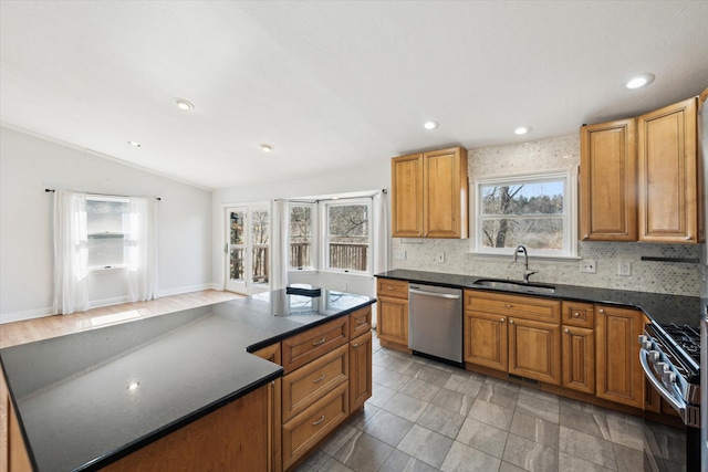 kitchen with a center island, vaulted ceiling, decorative backsplash, appliances with stainless steel finishes, and a sink