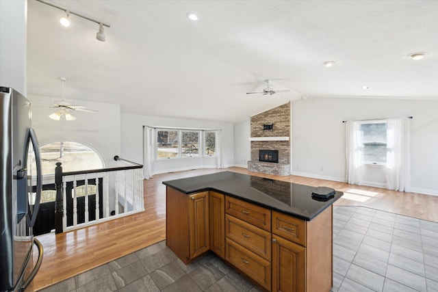 kitchen with plenty of natural light, a brick fireplace, lofted ceiling, and stainless steel refrigerator with ice dispenser