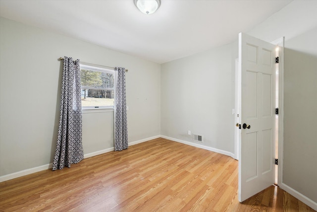 empty room with visible vents, light wood-style flooring, and baseboards