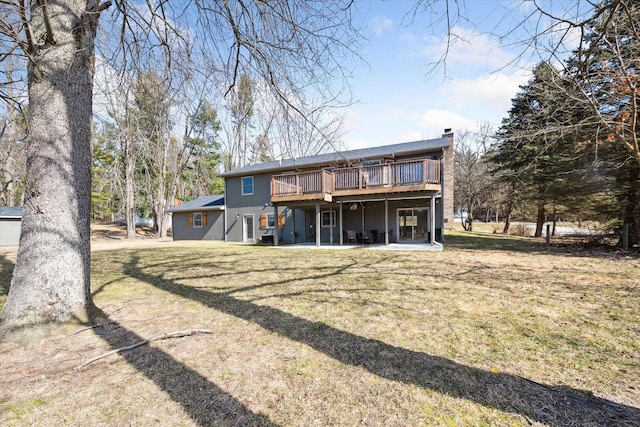 rear view of house with a wooden deck, a chimney, and a yard