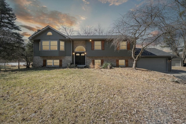 split foyer home featuring a front yard, brick siding, and driveway