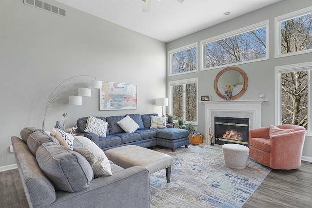 living area featuring visible vents, wood finished floors, a towering ceiling, and a fireplace