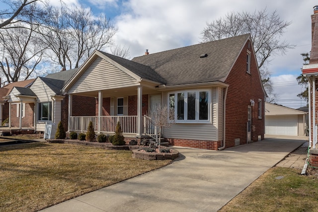 view of front facade featuring an outbuilding, a front yard, roof with shingles, covered porch, and a garage