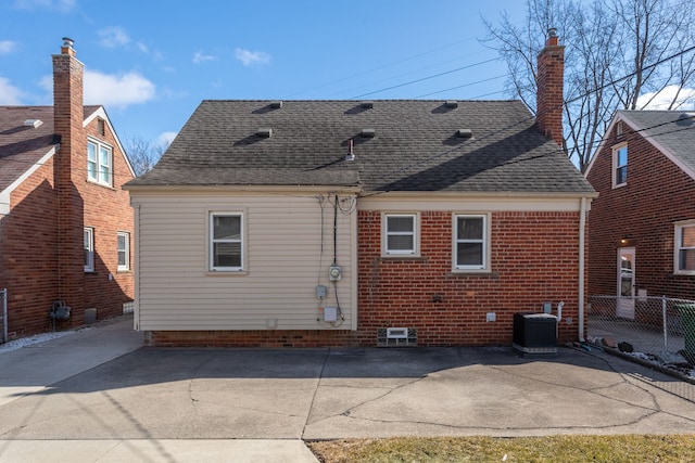 back of property with a patio, fence, roof with shingles, central AC, and brick siding