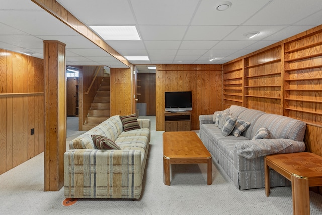 living room with built in features, stairway, wood walls, and carpet flooring