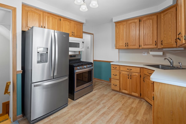 kitchen featuring light wood-type flooring, a sink, light countertops, appliances with stainless steel finishes, and brown cabinets