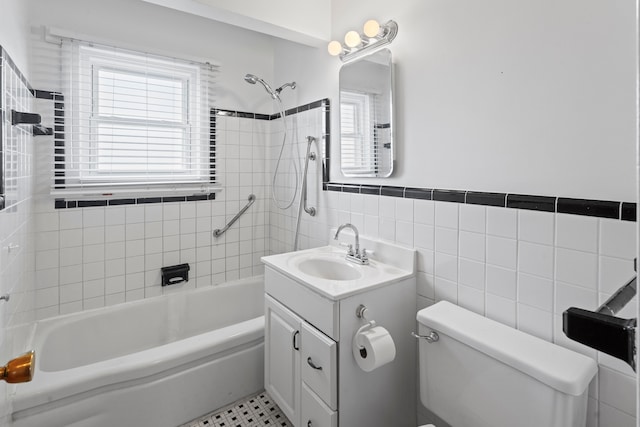 bathroom featuring vanity, a wainscoted wall,  shower combination, tile walls, and toilet