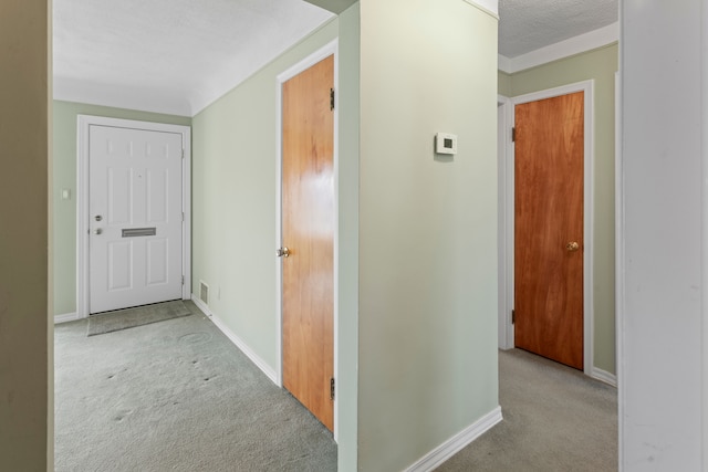 hall with visible vents, baseboards, carpet, and a textured ceiling