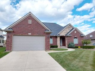 view of front of home with a garage, brick siding, concrete driveway, and a front lawn