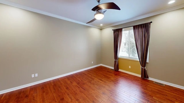 empty room with wood finished floors, baseboards, visible vents, ornamental molding, and ceiling fan