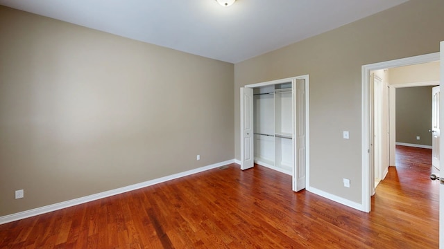 unfurnished bedroom featuring a closet, baseboards, and wood finished floors