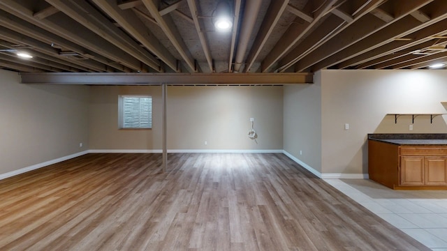 below grade area with baseboards and light wood-type flooring