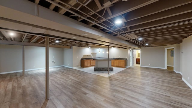 finished basement featuring light wood-type flooring and baseboards