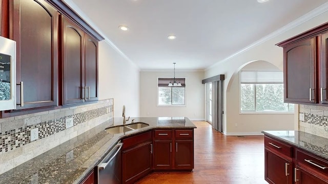 kitchen featuring reddish brown cabinets, ornamental molding, stainless steel dishwasher, and a sink