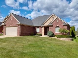 ranch-style house featuring brick siding, an attached garage, driveway, and a front yard