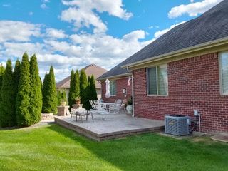 rear view of house with a patio, brick siding, and a lawn