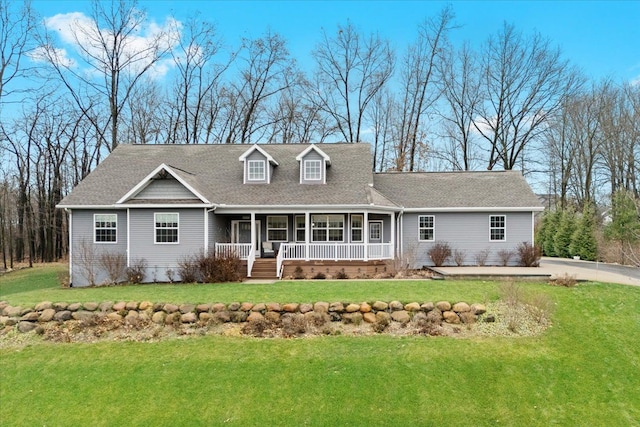 new england style home with roof with shingles, covered porch, and a front yard