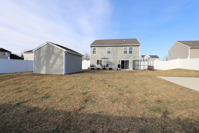 rear view of property featuring a fenced backyard, a lawn, and an outdoor structure