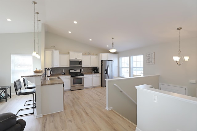 kitchen with light wood-style flooring, a sink, appliances with stainless steel finishes, a breakfast bar area, and a peninsula