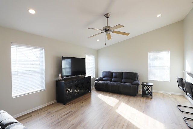 living room featuring light wood-type flooring, lofted ceiling, and a healthy amount of sunlight