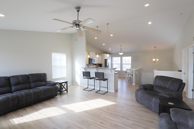 living area with baseboards, light wood-type flooring, ceiling fan with notable chandelier, recessed lighting, and high vaulted ceiling