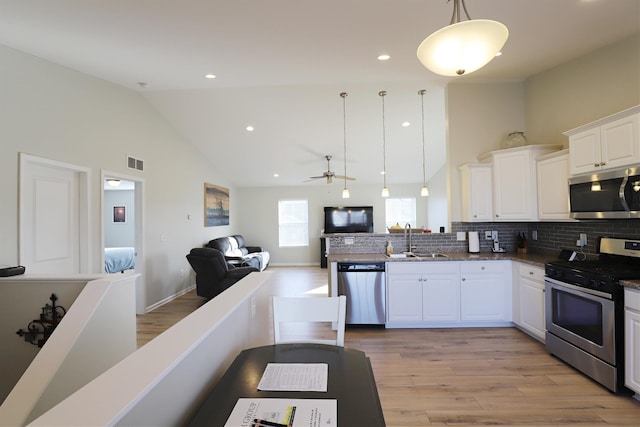 kitchen with open floor plan, stainless steel appliances, light wood-type flooring, and a sink