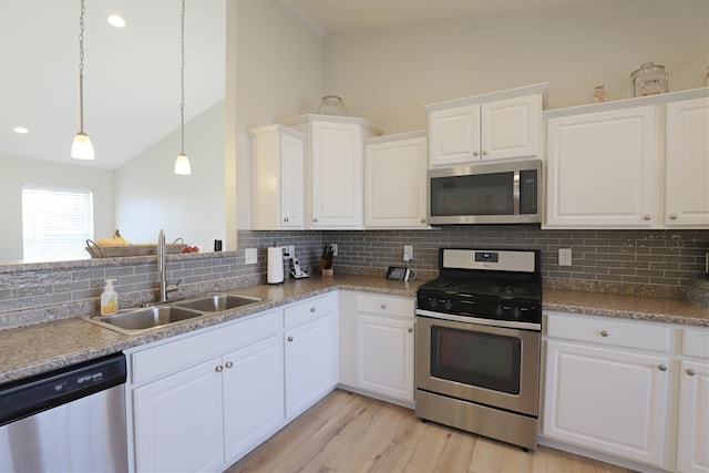 kitchen featuring backsplash, white cabinets, stainless steel appliances, and a sink