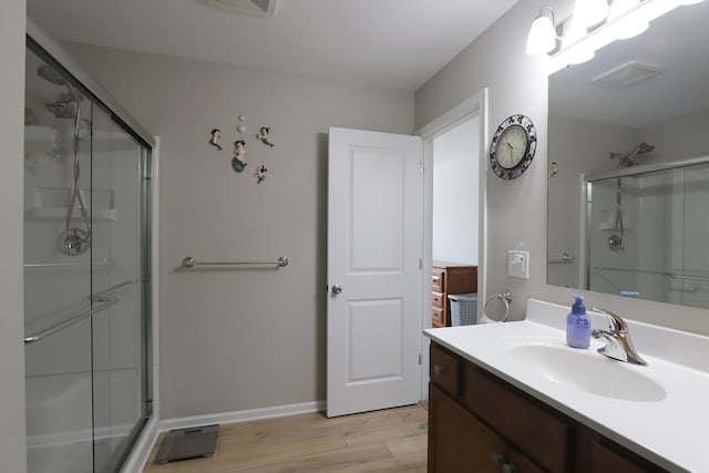 full bathroom with a shower stall, vanity, baseboards, and wood finished floors