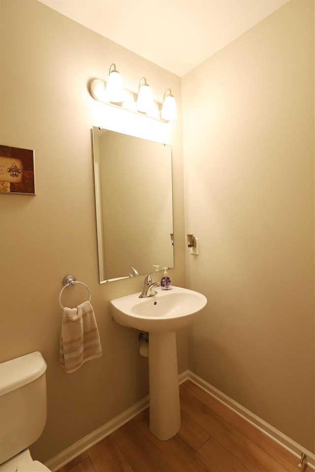 bathroom featuring a sink, toilet, baseboards, and wood finished floors