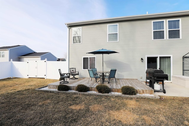 rear view of property featuring a gate, a lawn, a wooden deck, and fence