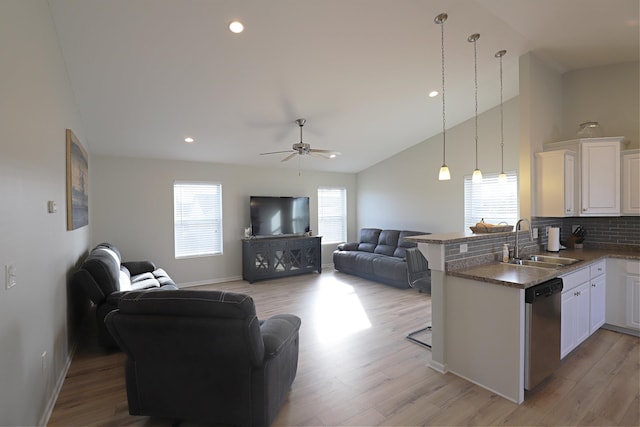 kitchen featuring a sink, open floor plan, a peninsula, light wood finished floors, and dishwasher