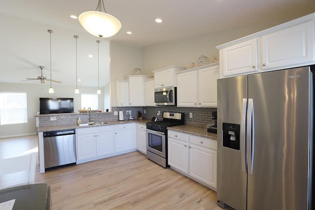 kitchen with plenty of natural light, a sink, decorative backsplash, appliances with stainless steel finishes, and open floor plan