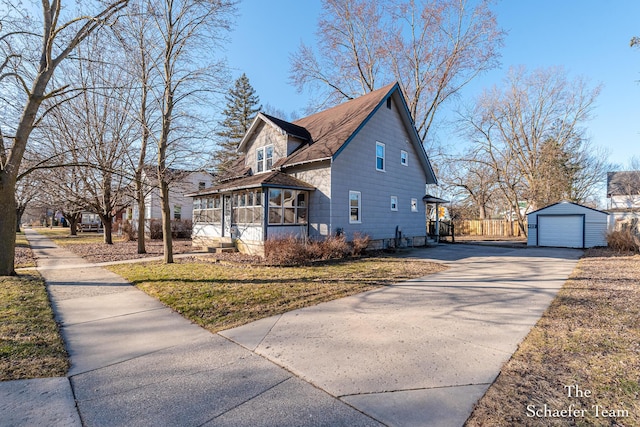 view of side of home featuring an outbuilding, driveway, a garage, and a sunroom