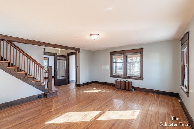 spare room featuring stairway, radiator, baseboards, and hardwood / wood-style floors