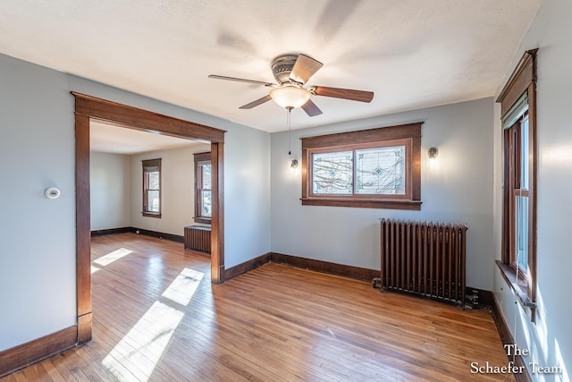 unfurnished room featuring radiator heating unit, baseboards, and wood-type flooring