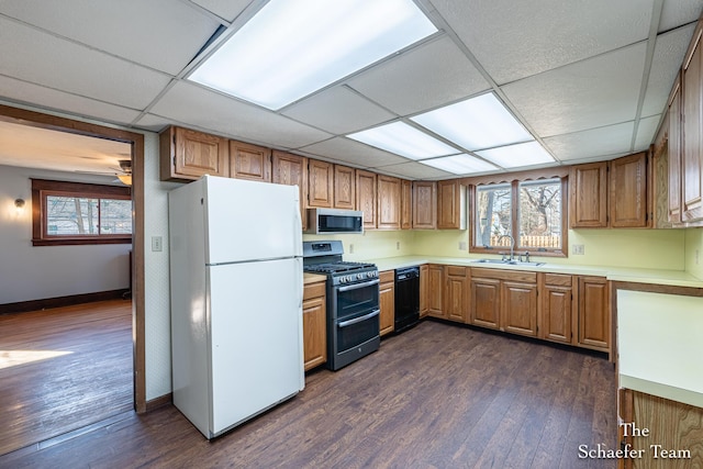 kitchen featuring a sink, dark wood-style flooring, a drop ceiling, and stainless steel appliances