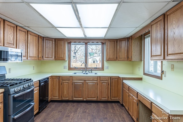 kitchen with a sink, stainless steel microwave, double oven range, black dishwasher, and light countertops