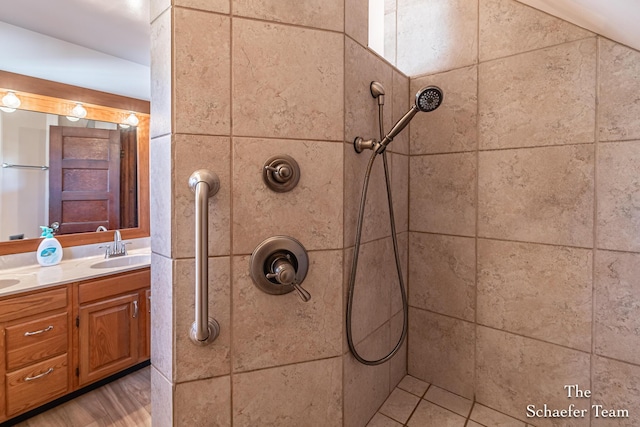 full bathroom featuring a tile shower, double vanity, and a sink