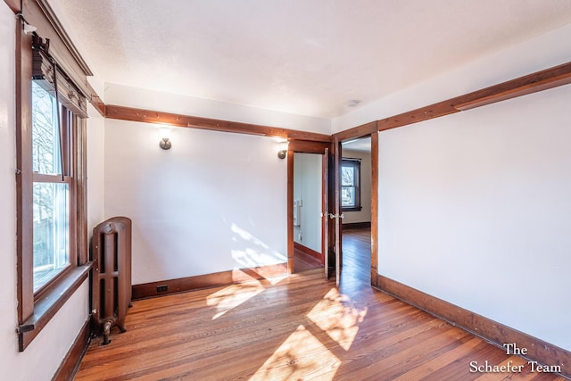 unfurnished room featuring radiator, baseboards, and hardwood / wood-style flooring