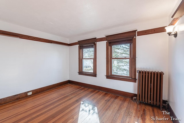 unfurnished room featuring radiator, baseboards, and hardwood / wood-style flooring