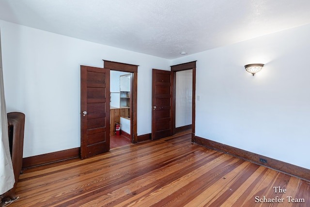 spare room with baseboards and wood-type flooring