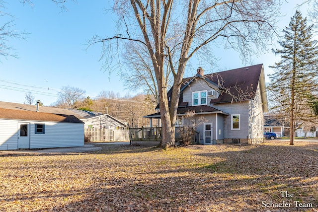 back of property featuring a wooden deck, a chimney, and fence