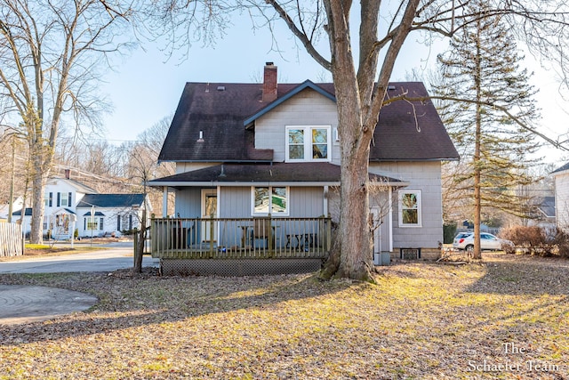 rear view of property with a porch, a chimney, and a shingled roof