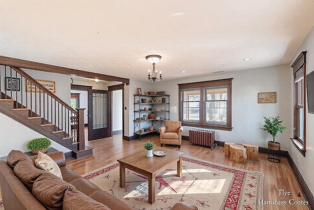 living room featuring stairs, an inviting chandelier, radiator, and wood finished floors