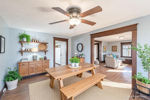 dining room with baseboards, radiator, ceiling fan, and dark wood-style flooring