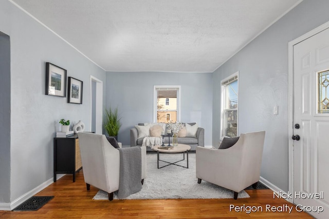 living area with visible vents, baseboards, and wood finished floors