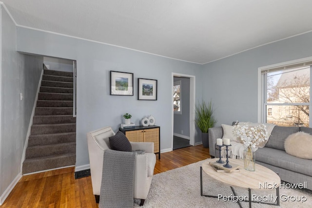 living area featuring baseboards, wood finished floors, and stairs