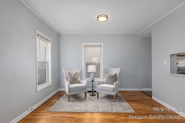 living area with baseboards, wood finished floors, and crown molding