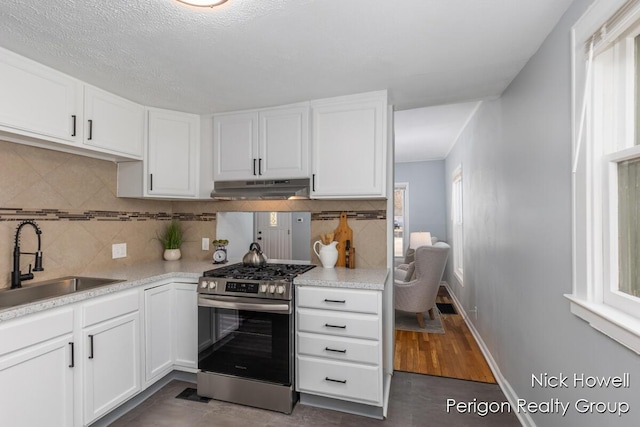 kitchen with under cabinet range hood, plenty of natural light, stainless steel range with gas stovetop, and a sink