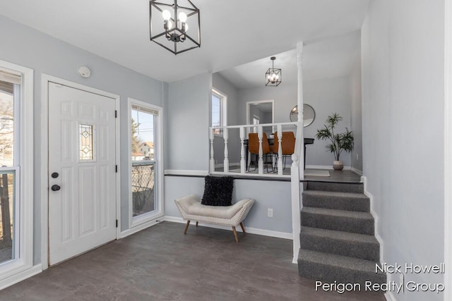 entryway featuring concrete floors, baseboards, an inviting chandelier, and stairs